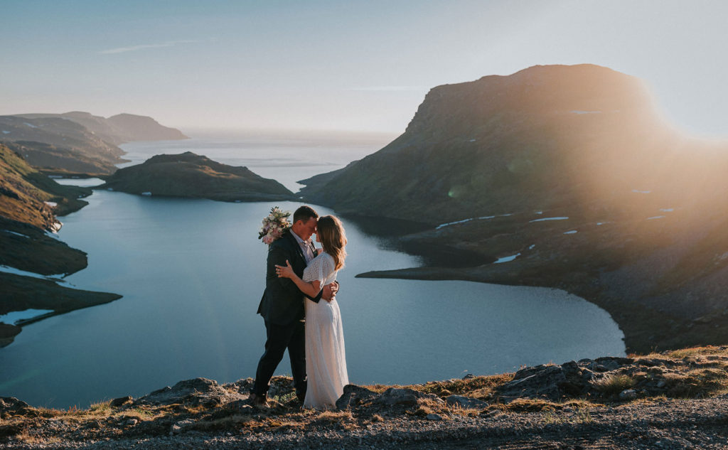 Bride and groom celebrating their intimate wedding at Sørøya island in Norway with a stunning sunset in mountains