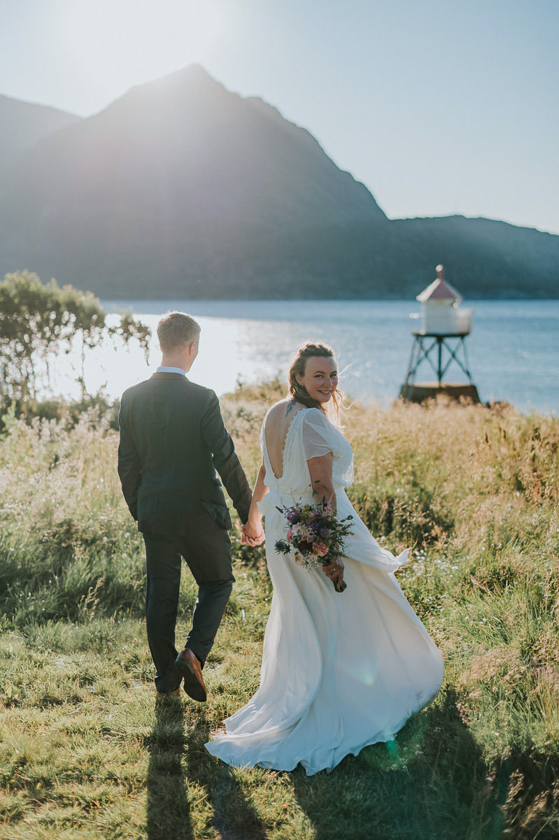 Nydelig brudepar spaserer i fjæra og går mot fyrlykt i Øksfjord Finnmark på en nydelig sommerkveld