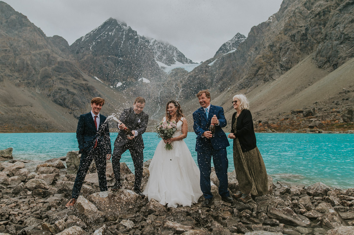 Bride and groom have just eloped on a glacier lake in Lyngen Alps Norway and are popping up champagne with their family