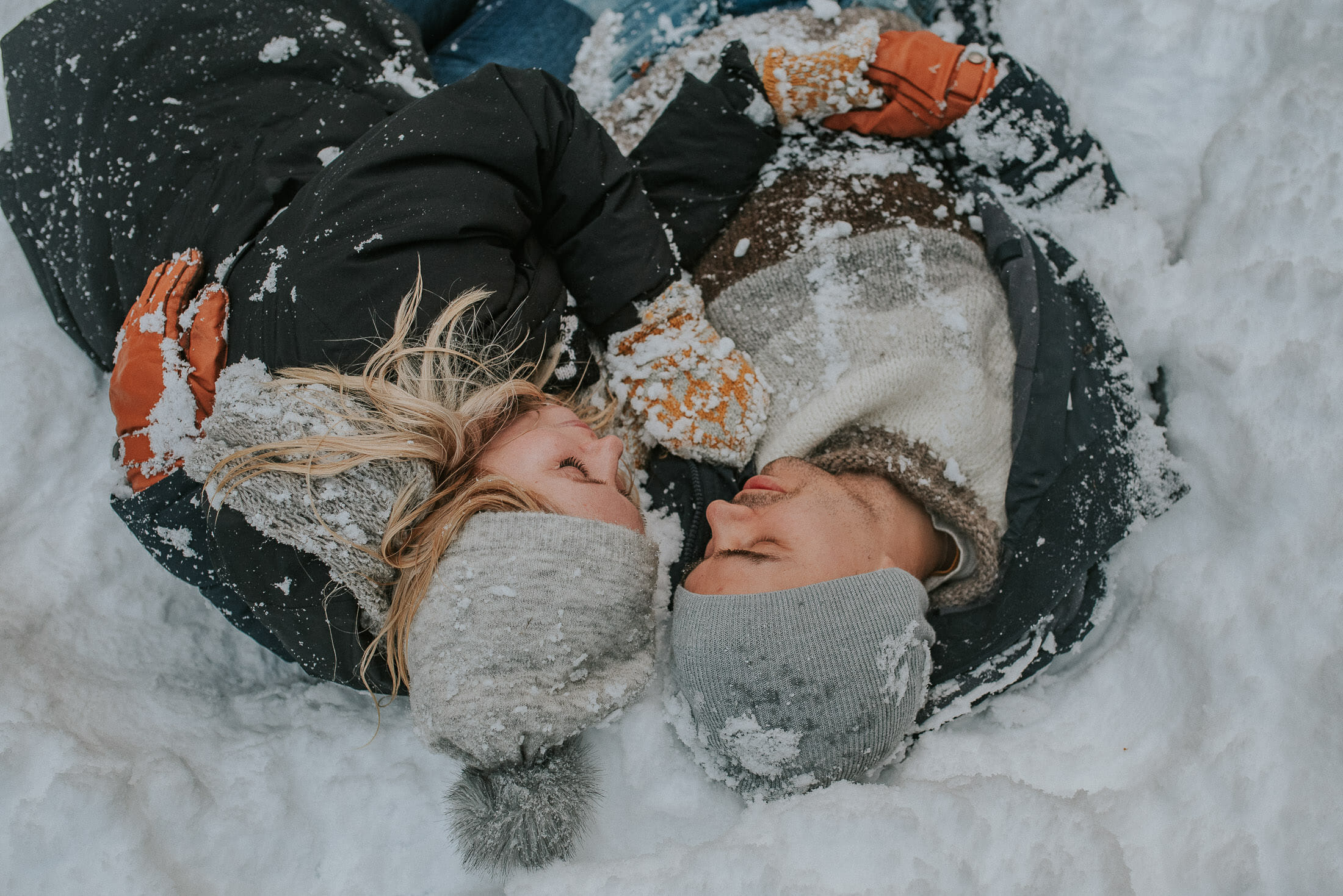 sweet couple laying in the snow on their winter engagement session in Skjervøy