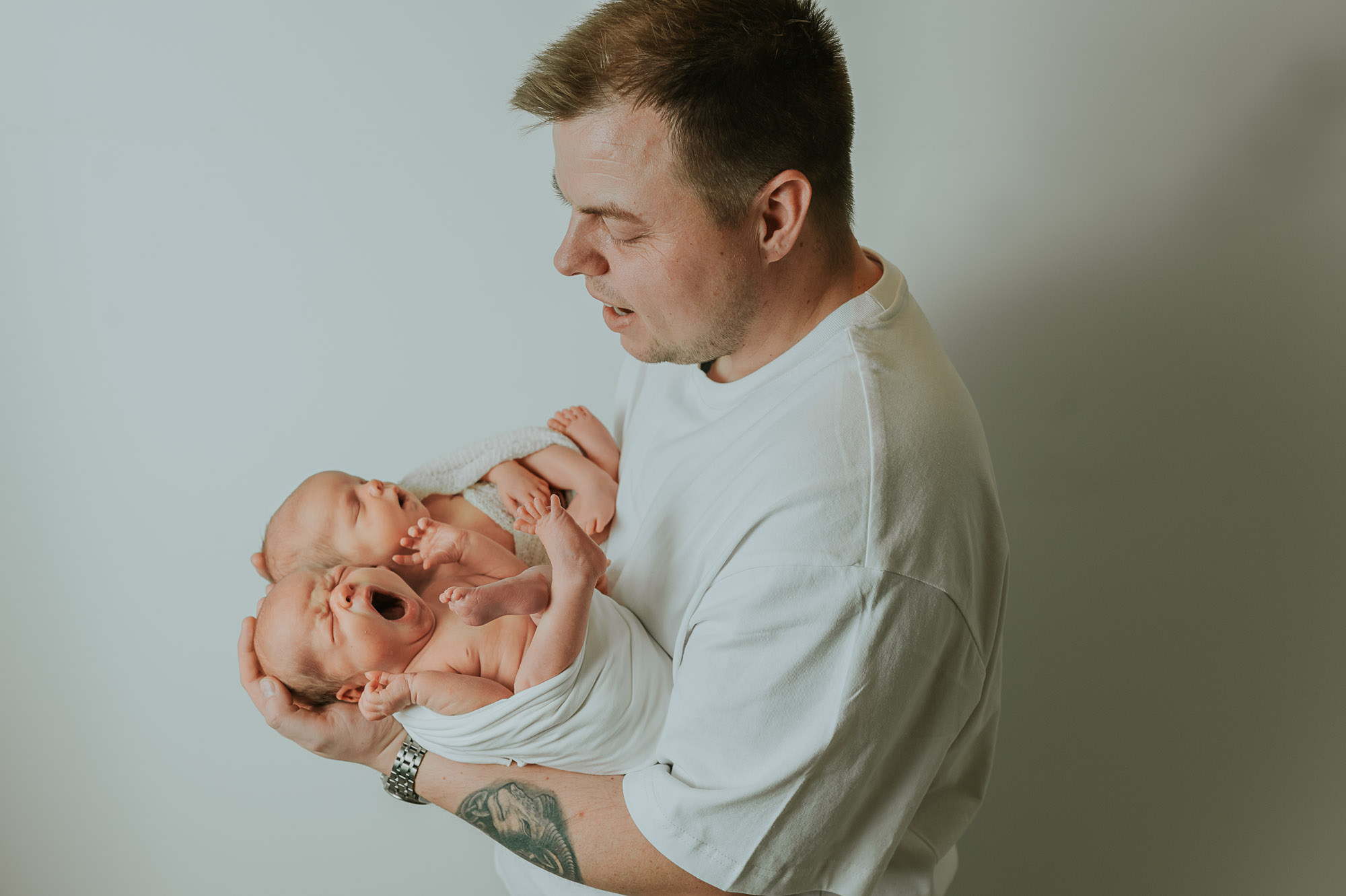 Nybakt far holder nyfødte tvillinger i hendene sine