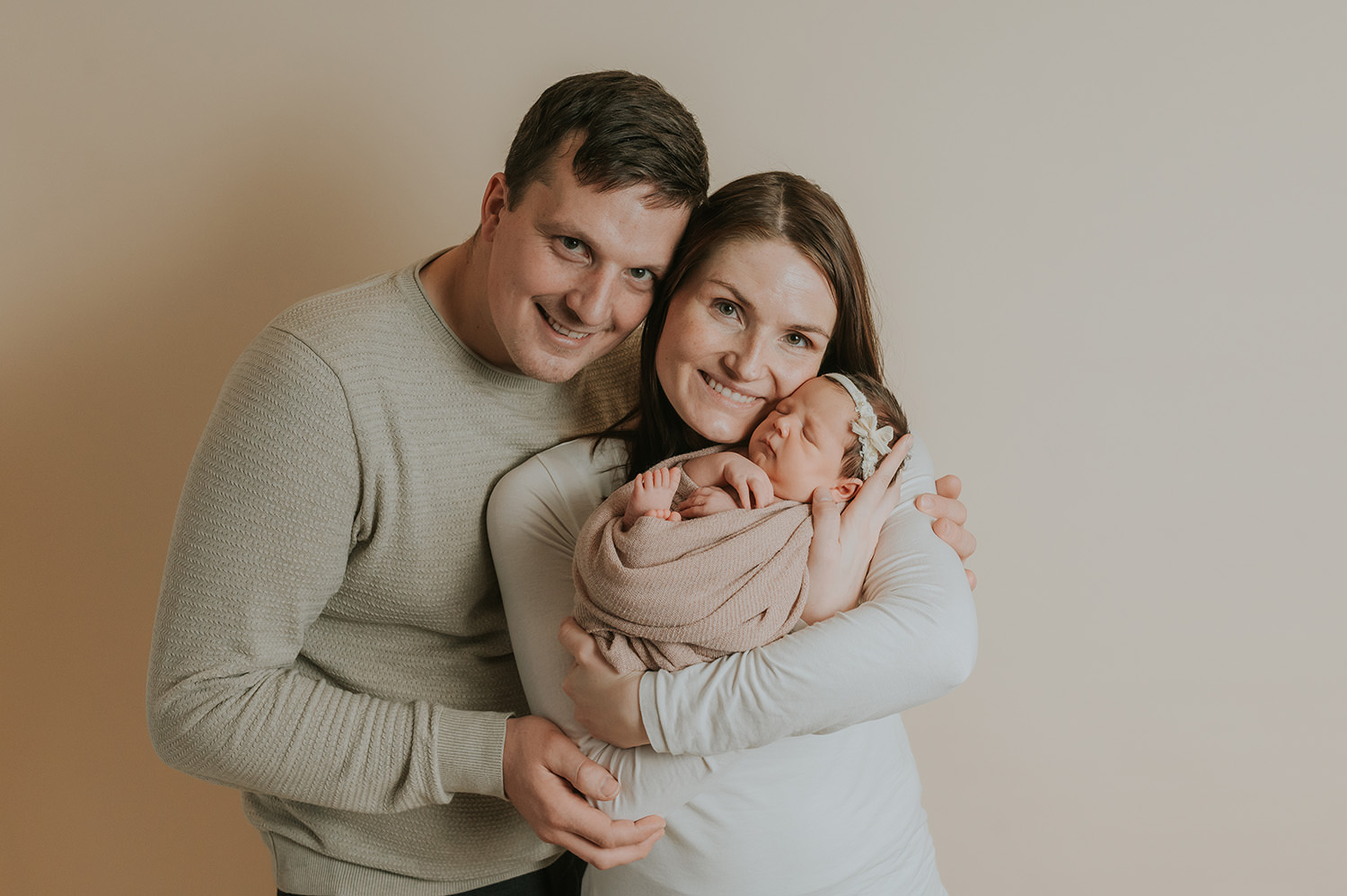 Fint familiebilde med mor og far og nyfødt jente på lyst fotobakgrunn