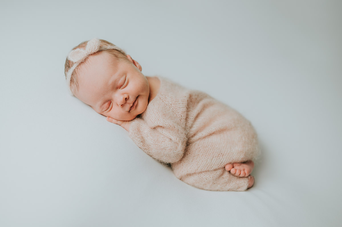 Nyfødt jente i rosa ulldrakt sover søtt på nyfødtfoto i fotostudio i Alta hos fotograf TS Foto Design