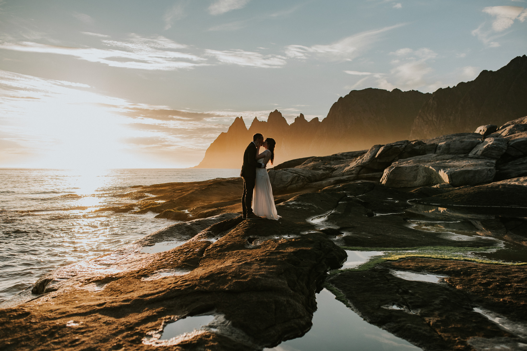 Bride and groom kissing in the midnight sun and with a stunning background of Senja in Norway at the end of their elopement day