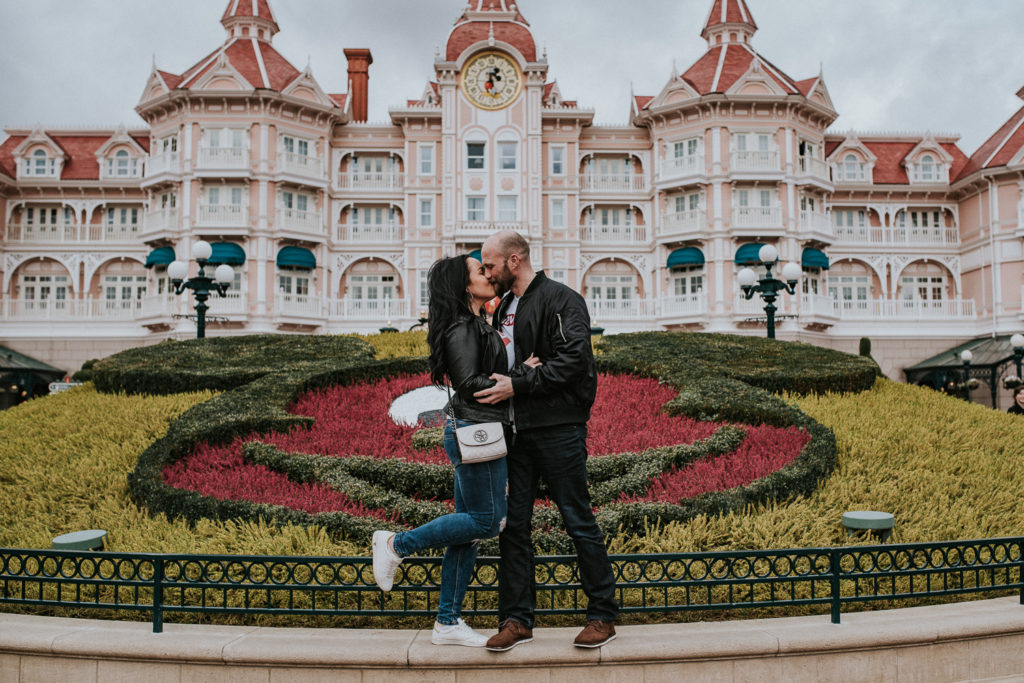 Beautiful couple is kissing each other in front of Disneyland Castle - couple Honeymoon photoshoot in Disneyland Paris