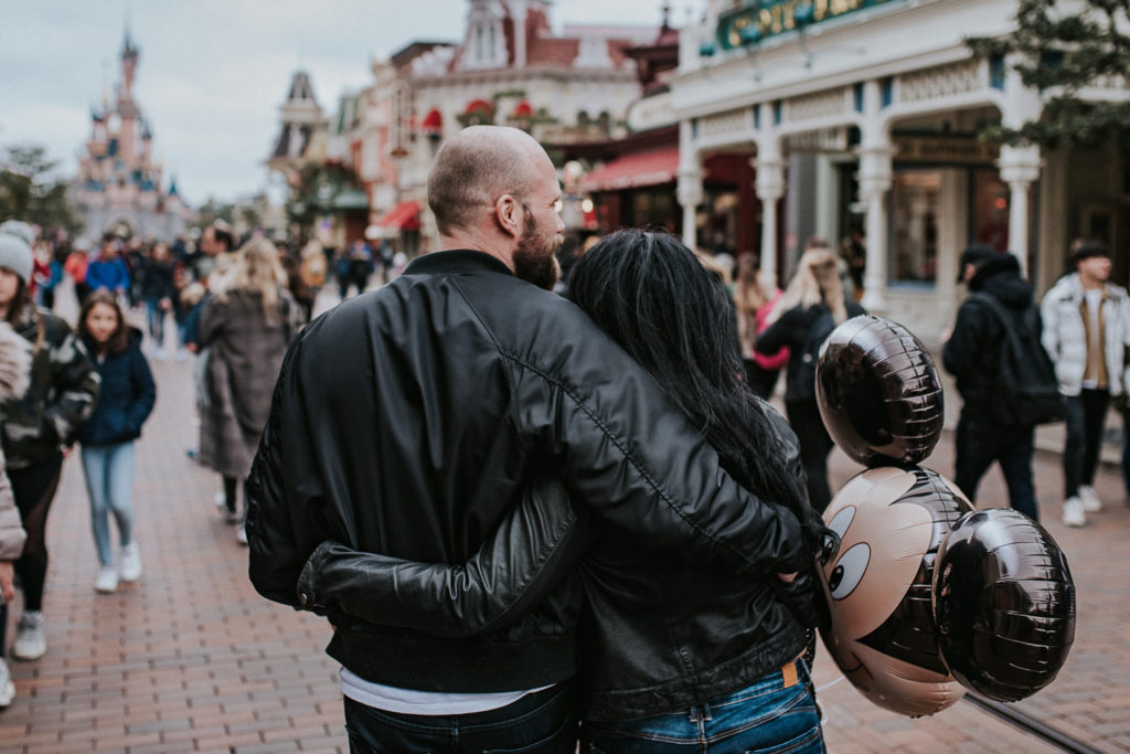 Sweet couple cuddling in front of the Disneyland castle in Paris, France. Honeymoon couple photo session 