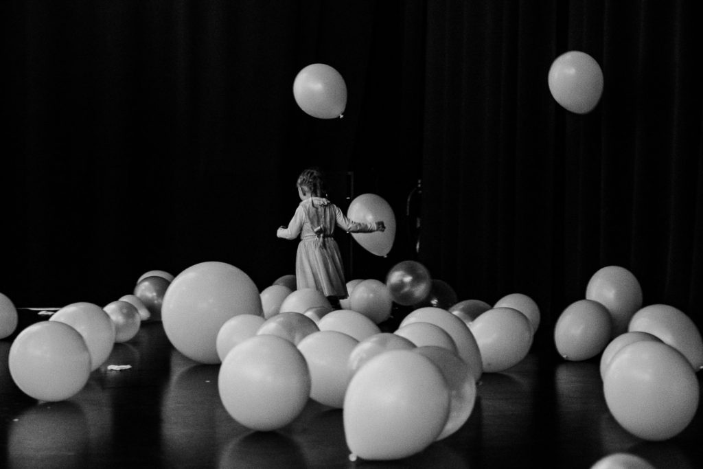 Little girl having fun at a wedding party and running between balloons