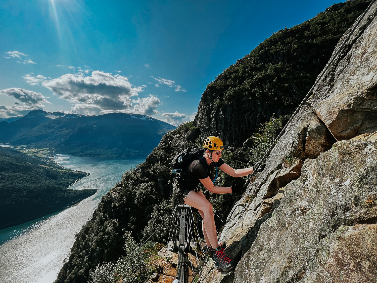 Young woman climbing via ferrata in Loen Norway on a sunny day