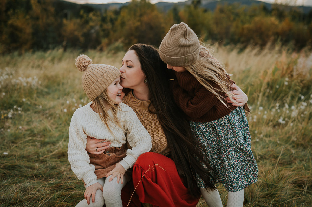 Family portrait of a mother and two daughters with a beautiful fall landscape in the background