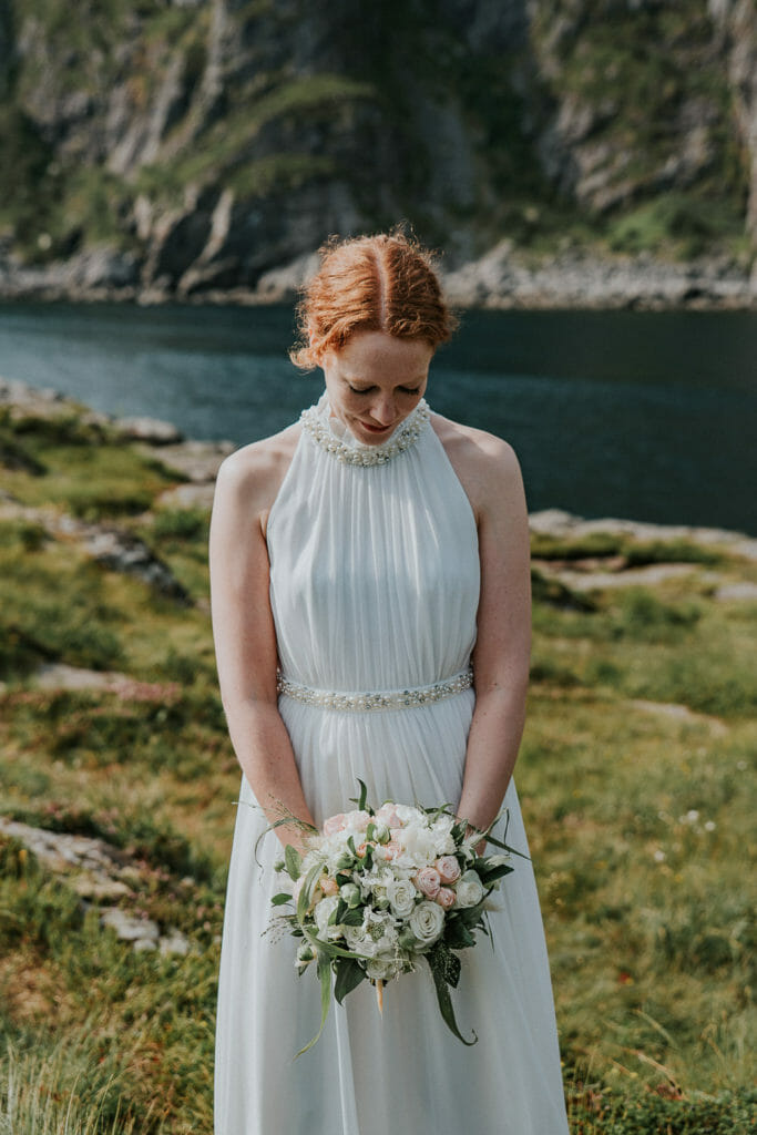 Beautiful bride with a wedding bouquet in white tones in front of mountains landscape in Lofoten Norway