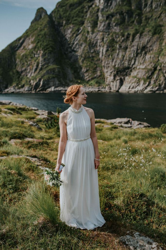 Beautiful bride in simple wedding dress in front of a beautiful mountain landscape in Lofoten Norway