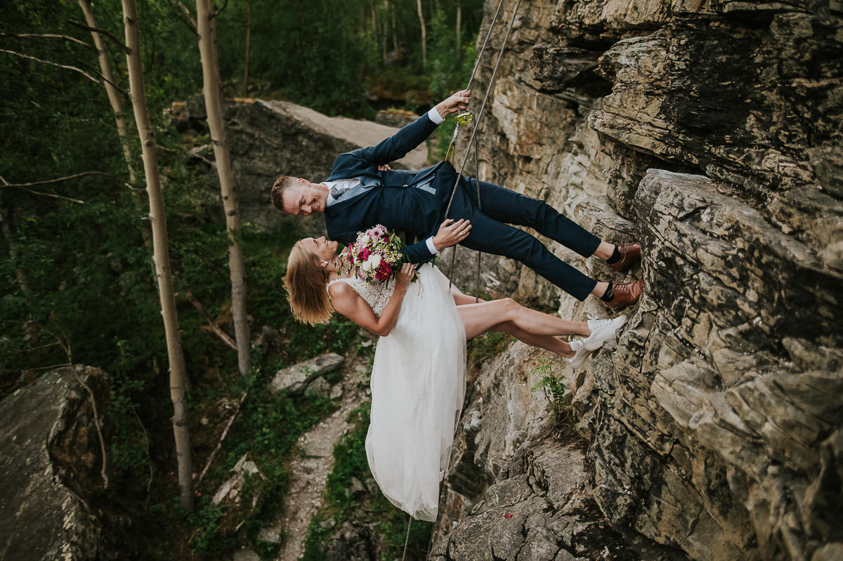Bride and groom climbing a mountain in their wedding attire in Alta Norway on the day of their adventure elopement in Alta