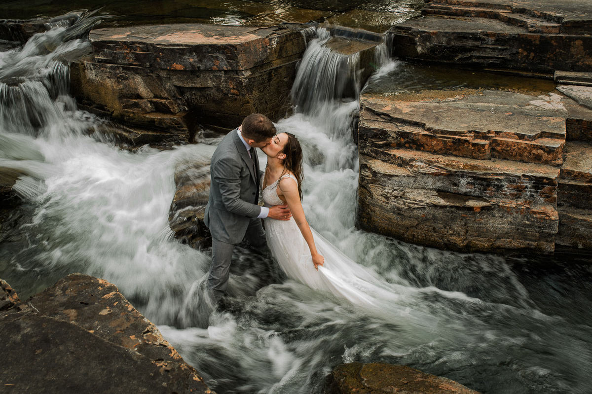 Bride and groom jumped in a river on their adventure elopement day in Alta Norway and kissing in the middle of the waterfall