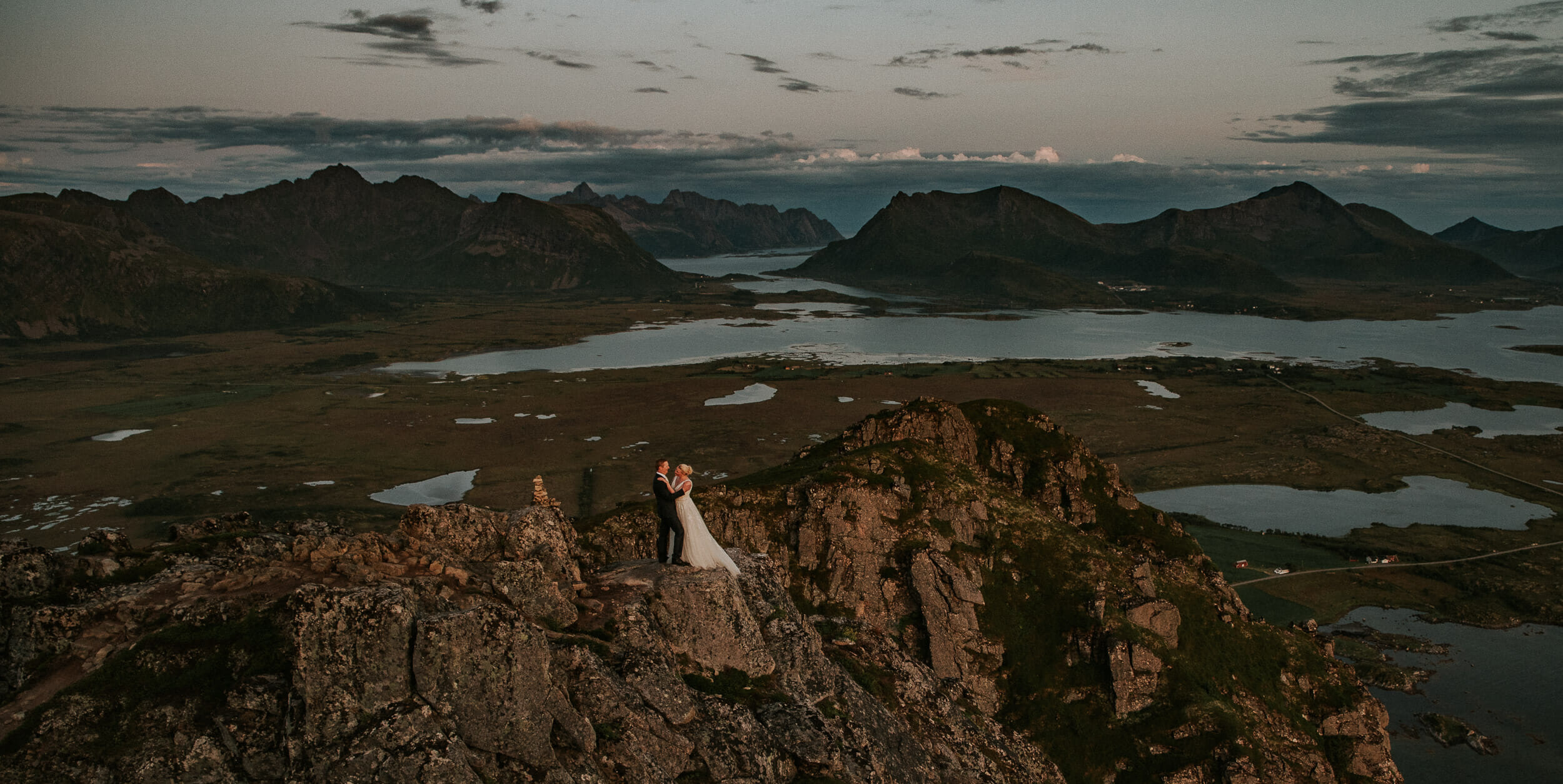 Bride and groom on a mountain cliff with a gorgeous view in Lofoten Norway