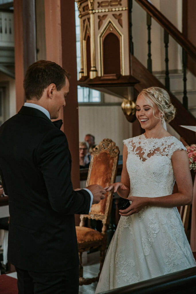 Vakkert øyeblikk i kirka på Finnsnes hvor brudeparet tar ringene på hverandre fotografert av profesjonell bryllupsfotograf TS Foto Design
