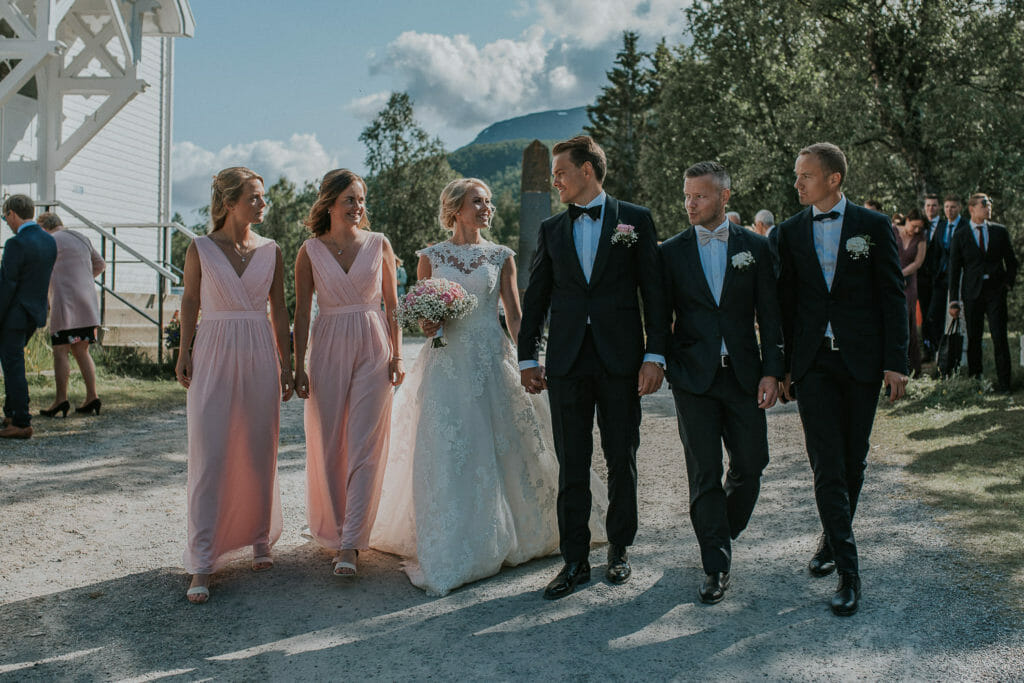 Bridesmaids and groomsmen walking with the bride and groom right after wedding ceremony in Senja while Senja wedding photographer photographs them