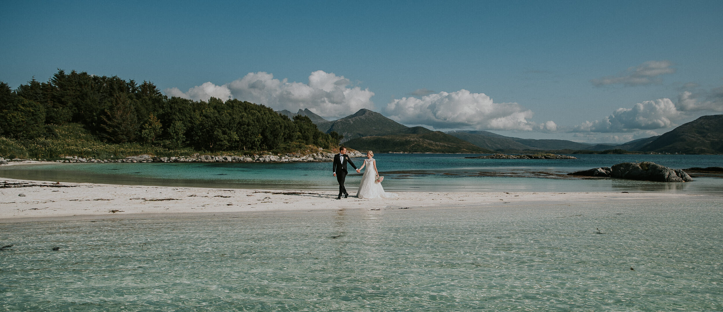 Bride and groom walking on amazing white beach of Senja island in Norway