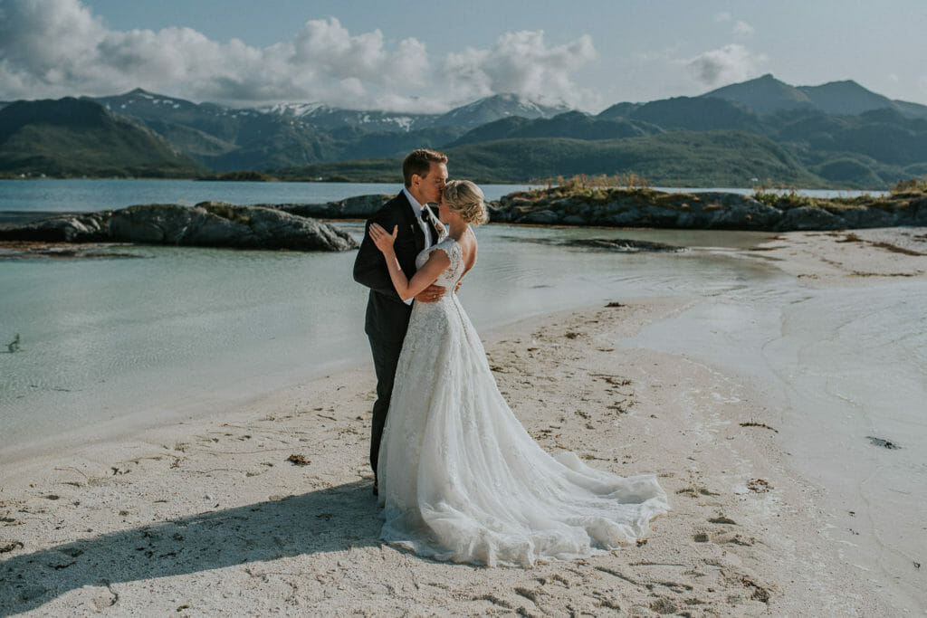 Bride and groom kissing on a beautiful beach at Færøya island outside of Senja