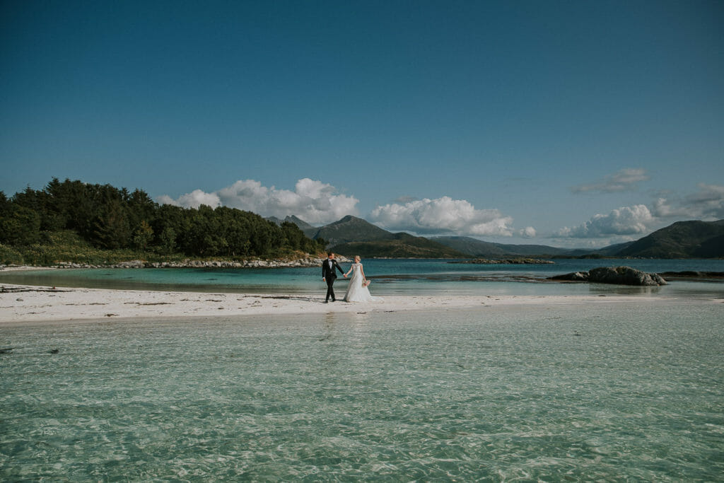 Bride and groom walking on a beautiful beach on Senja island - stunning elopement locations in Northern Norway