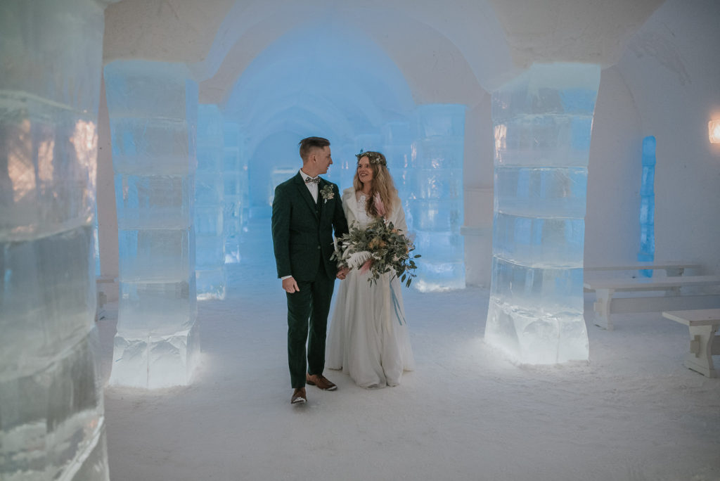 Bride and groom wandering around ice sculptures in ice hotel Sorrisniva in Alta Norway on their wedding day