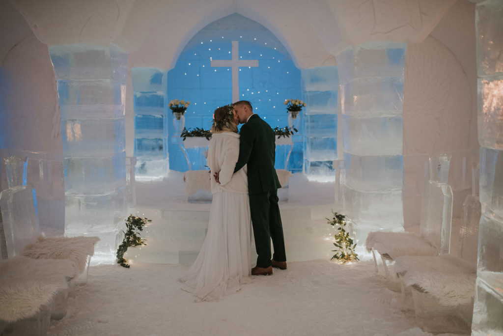 Bride and groom kissing in the ice chapel of ice hotel Sorrisniva Alta Norway