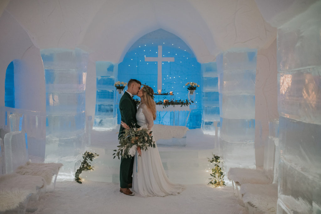 Cute couple kissing among ice and snow in the ice hotel in Alta Norway