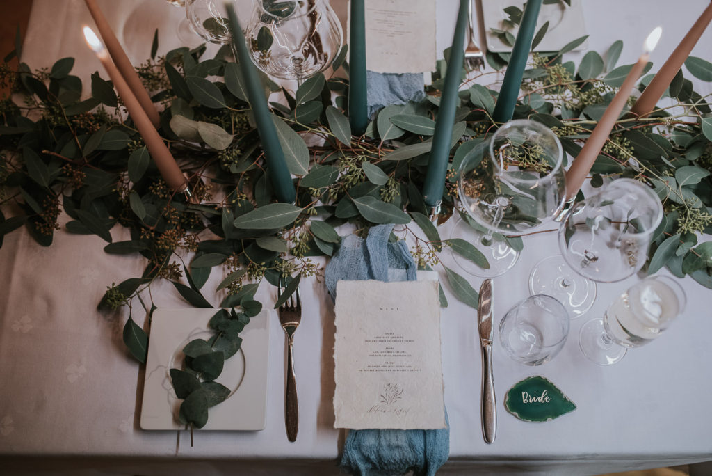 Amazing wedding table decorations in blue and beige colors with green leaf garland