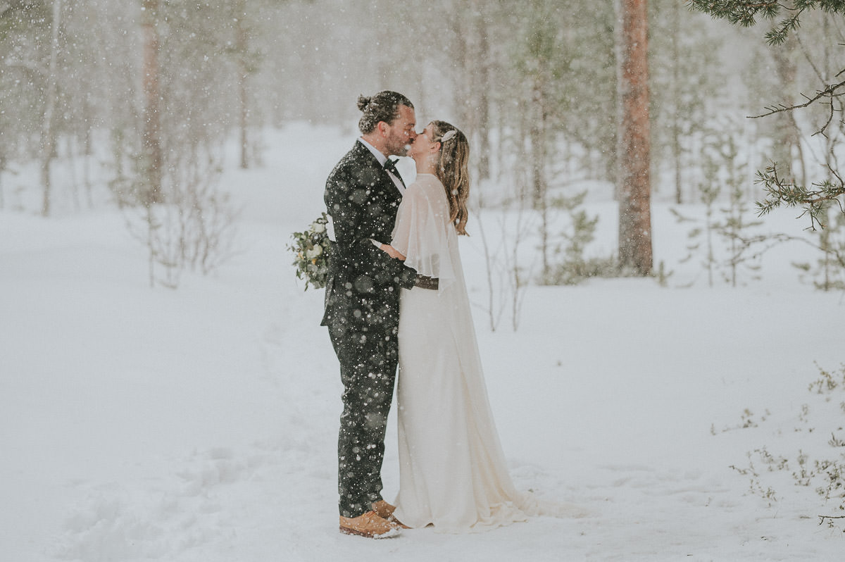 Beautiful bride and groom kissing under a blizzard winter storm in Alta Norway on the day of their elopement
