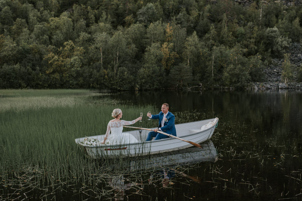 Bride and groom drinking champagne in the boat on a lake on their wedding day 