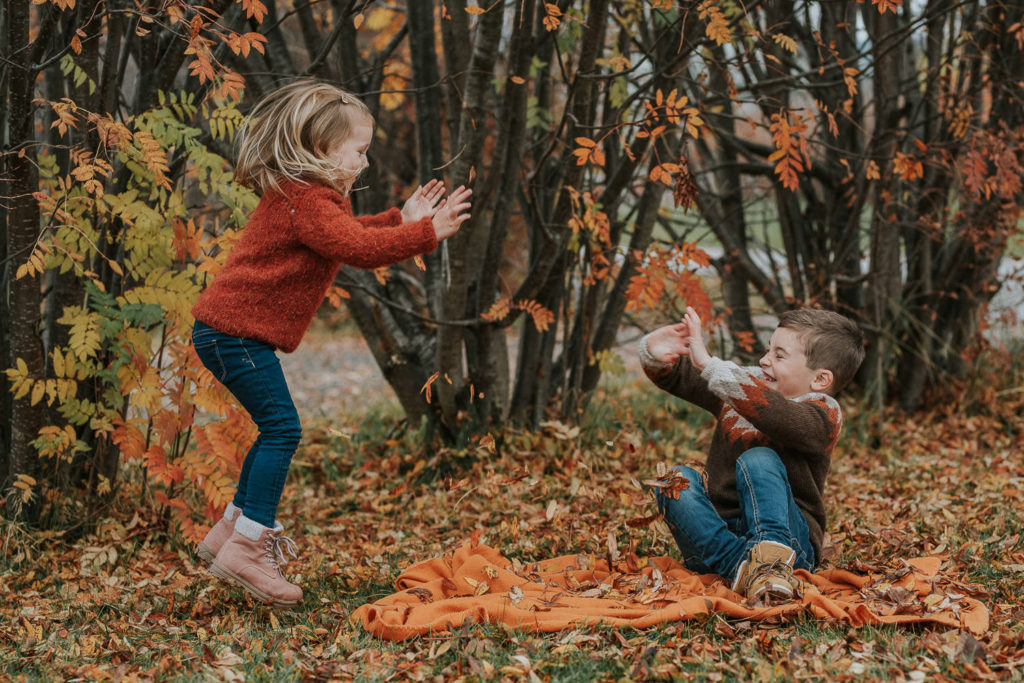 To glade barn leker med høstblader og ler på barnefotografering i Alta hos fotograf TS Foto Design - hvordan forberede barn til barnefotografering