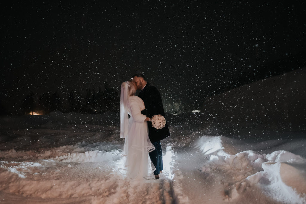 Vinterbryllup i mørketid - brudepar kysser hverandre under snefall