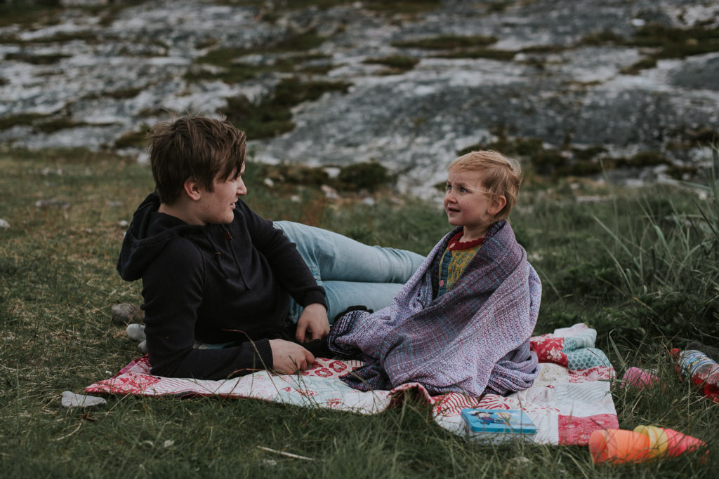 Bror og søster koser seg på picnic ved havet i Alta
