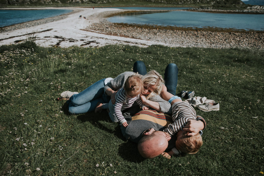 En familie ligger på gresset og nyter nord-norsk sol 