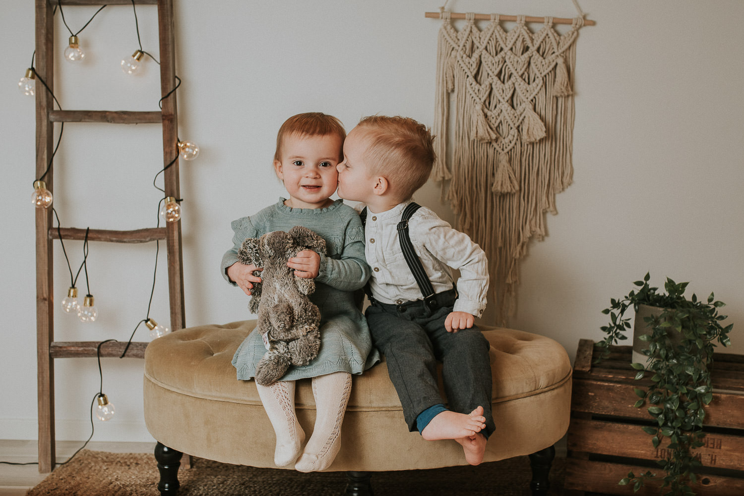 Søte søster og bror kysser hverandre på barnefotografering og familiefotografering i fotostudio i Alta