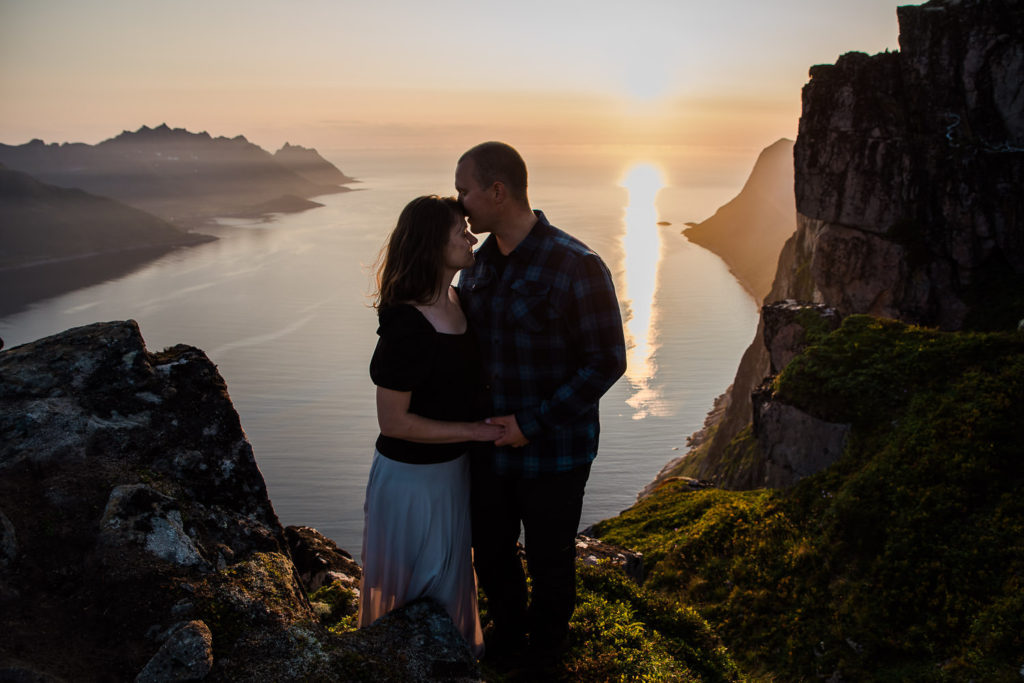 Beautiful couple enjoying last sun rays at a mountaintop Senja Norway