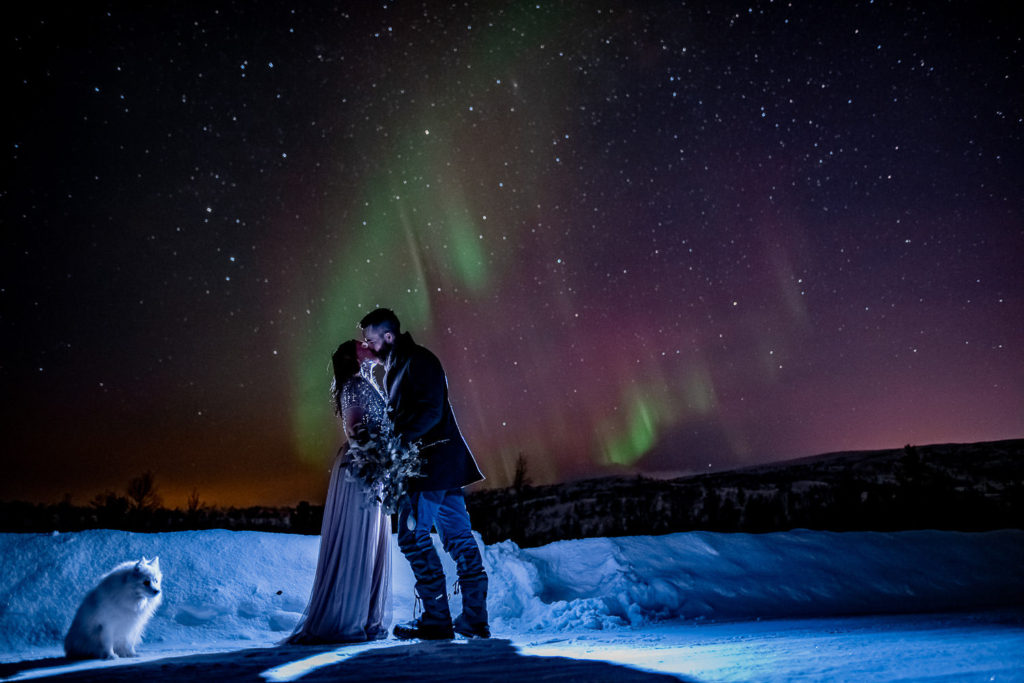 Bride and groom kissing under the northern lights on the day of their elopement
