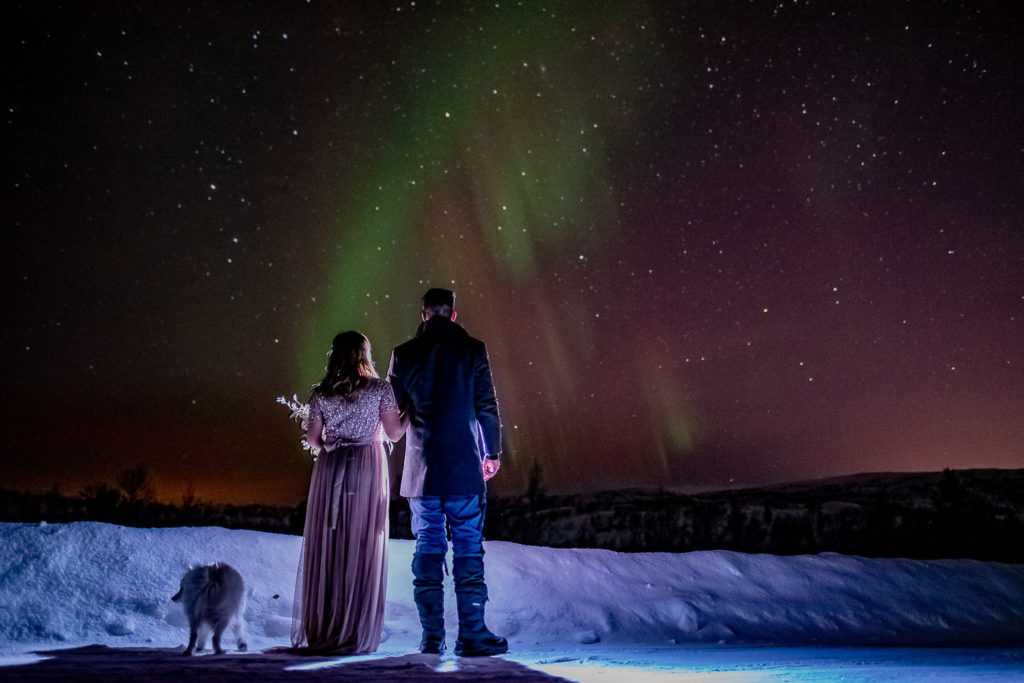 Bride and groom wathcing a beautiful Aurora borealis show on the day of their elopement in Northern Norway