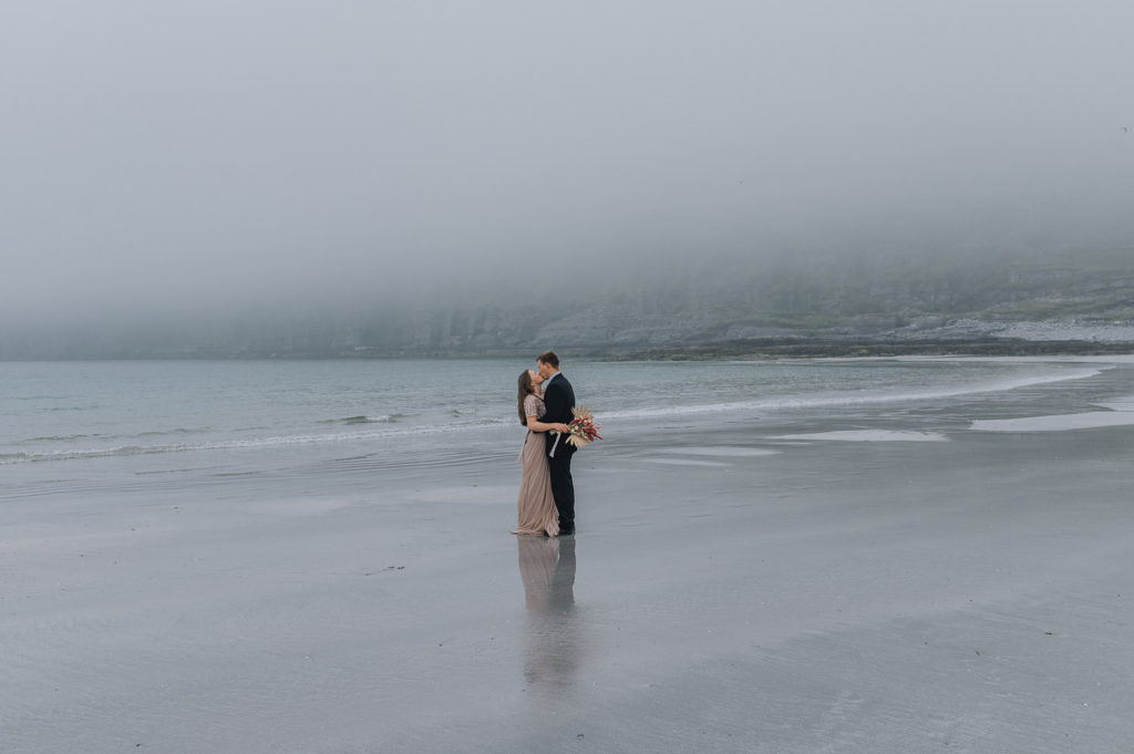 Beach elopement in Norway on a foggy night by the sea - bride and groom kissing each other