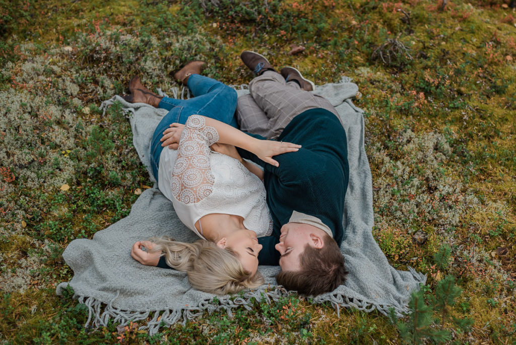 Beautiful couple laying on a blanket in a forest in Alta Norway  - fall engagement photo session