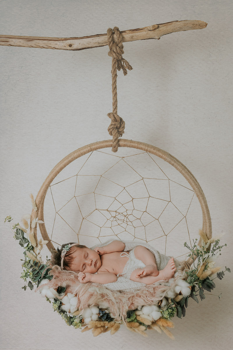 Nydelig nyfødt jente sover i en drømmefanger på nyfødtfotografering hos TS Foto Design i Alta
