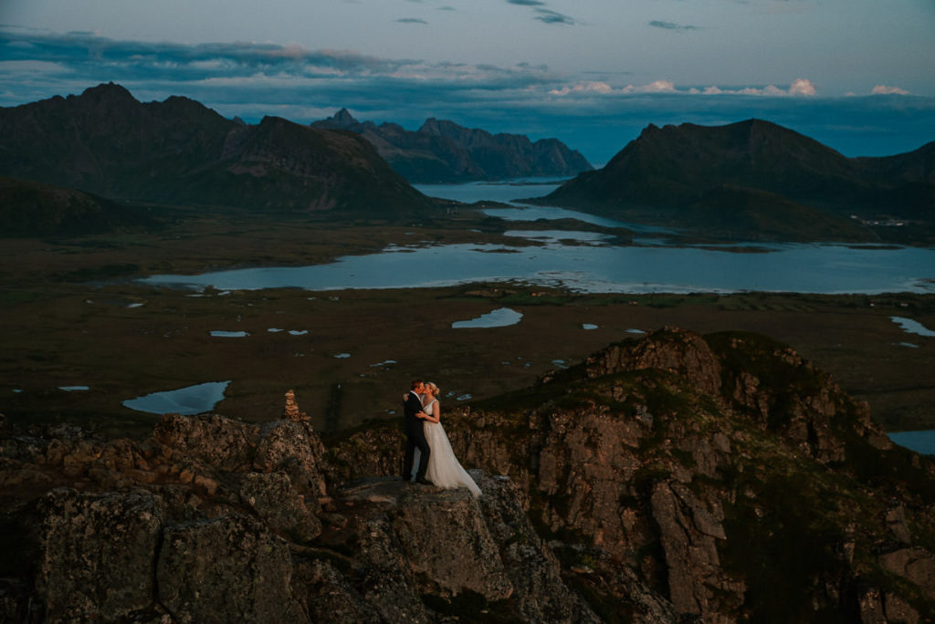 Bride and groom kissing each other with a stunning mountain view in Lofoten on the day of their adventure elopement