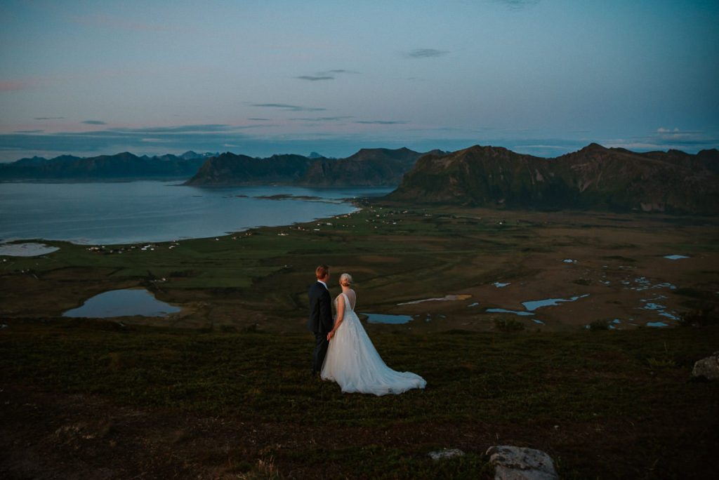 Bride and groom enjoying stunning views from a summit in Lofoten on their adventure elopement day