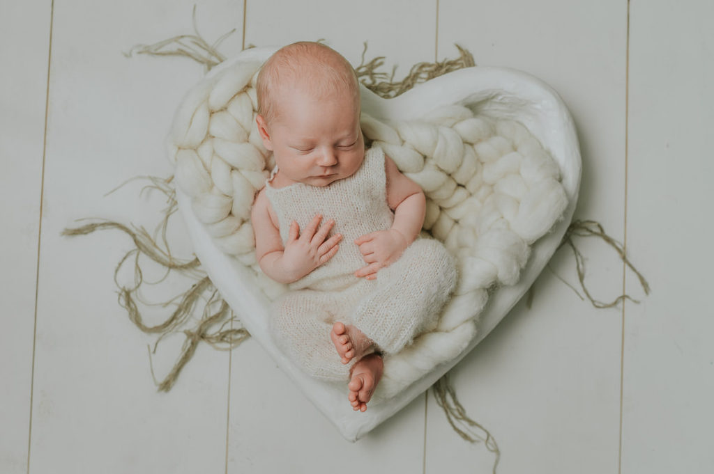 Søt baby gutt sover fredelig i et hjerteformet fotoprops