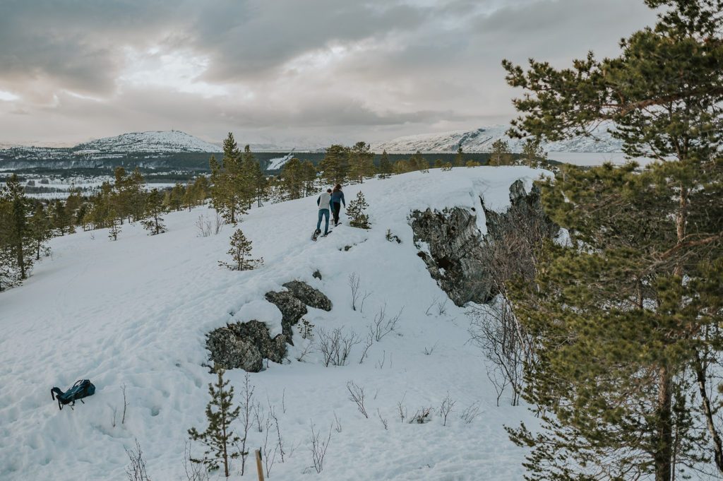 Snowshoeing engagement photo session in Alta, Norway - couple walking on snowshoes in the mountains