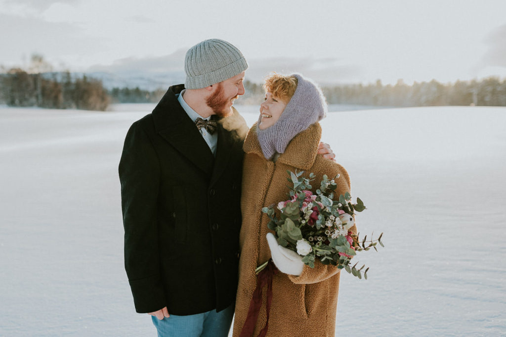 Bride and groom smiling to each other on the day of their intimate winter wedding in Alta Norway