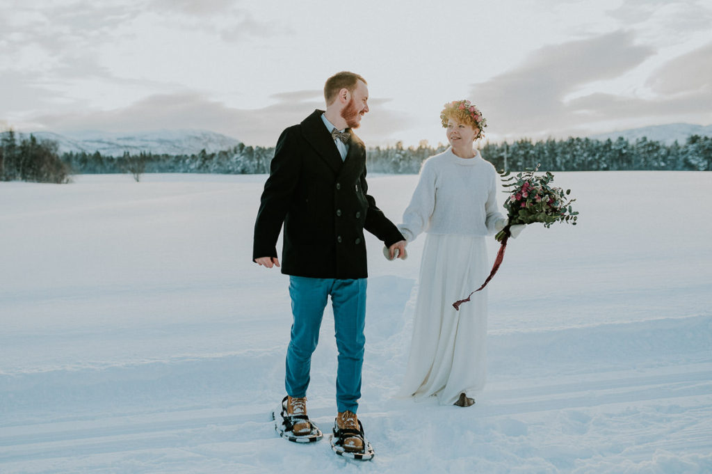 Bride and groom snowshoeing on the day of their winter elopement in Norway