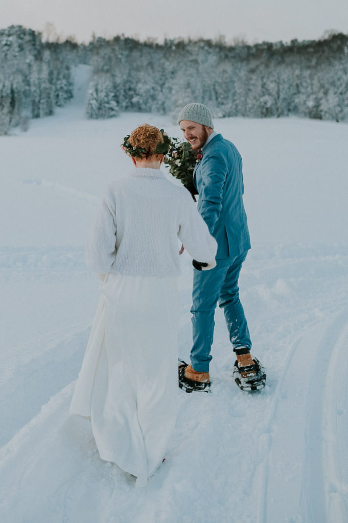 Bride and groom in front of snow covered winter forest on the day of their adventure winter elopement in Alta Norway