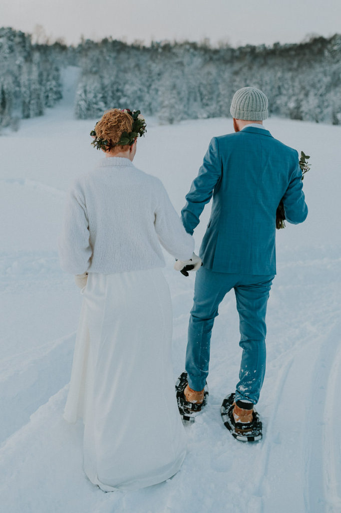 Bride and groom in front of snow covered winter forest on the day of their adventure nordic elopement in Alta Norway