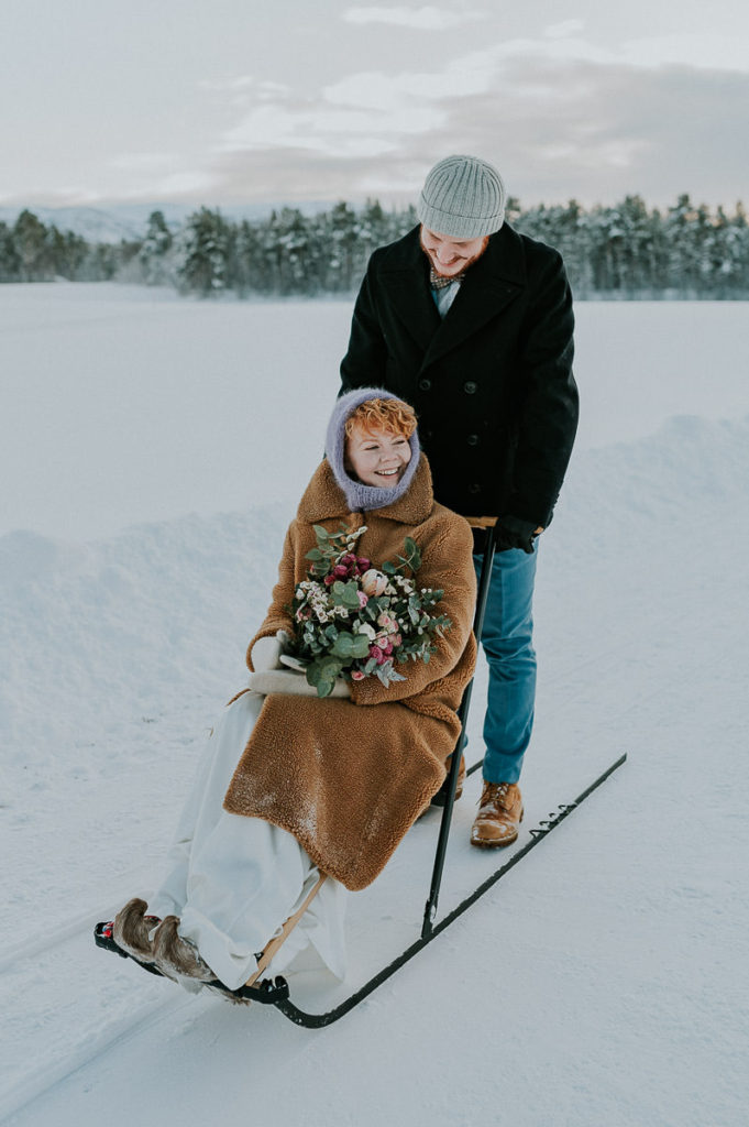 Bride and groom kicksleding in Northern Norway on the day of their winter elopement wedding 