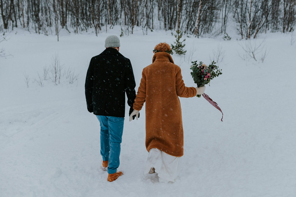 Bride and groom walking under the snow in Northern Noeway